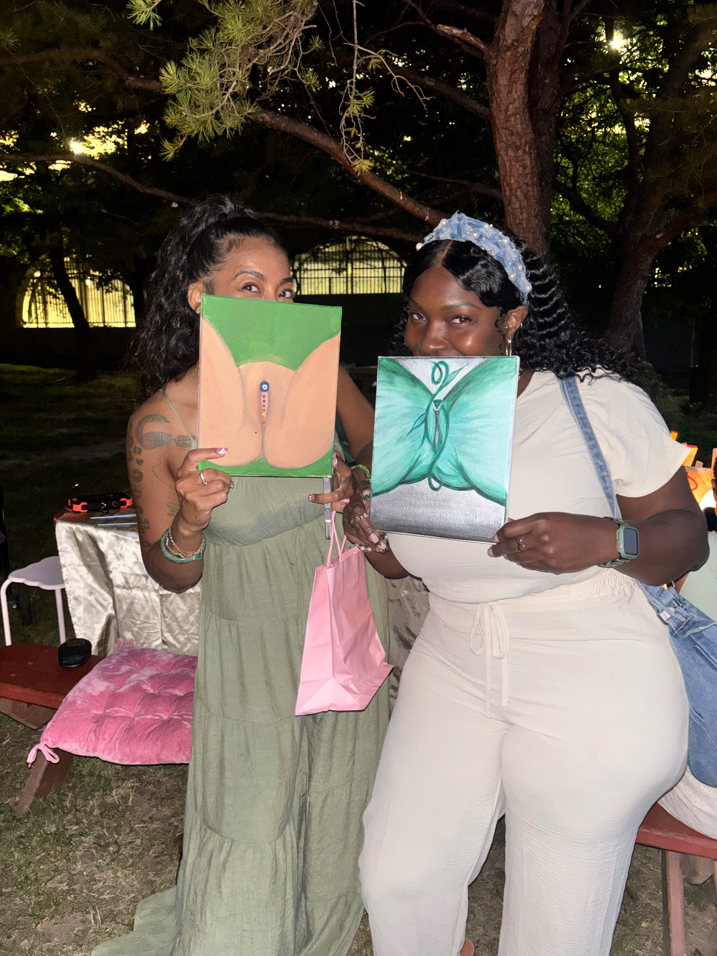 Two women holding their yoni paintings